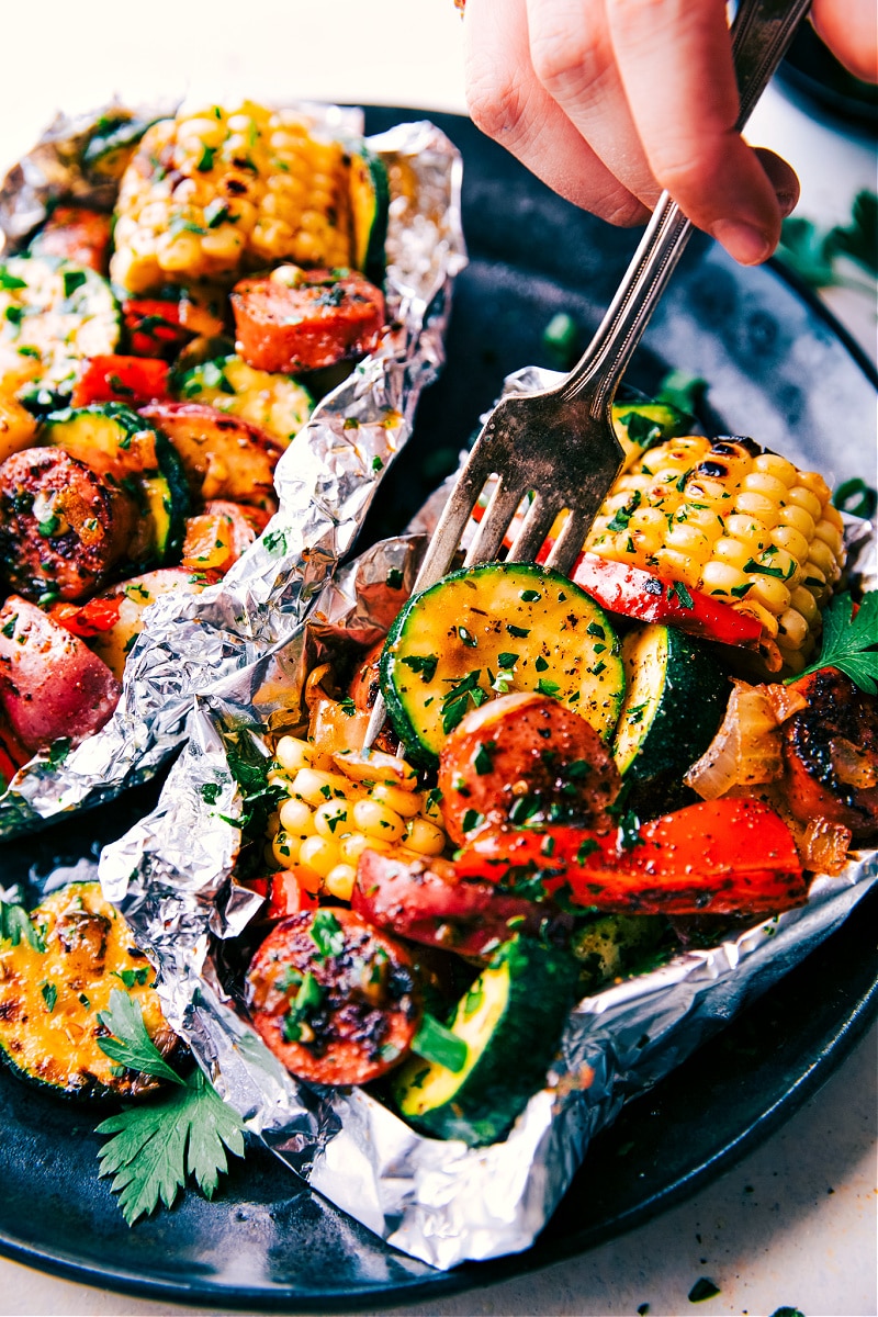 Image of the tin foil sausage and veggies with a fork full being taken