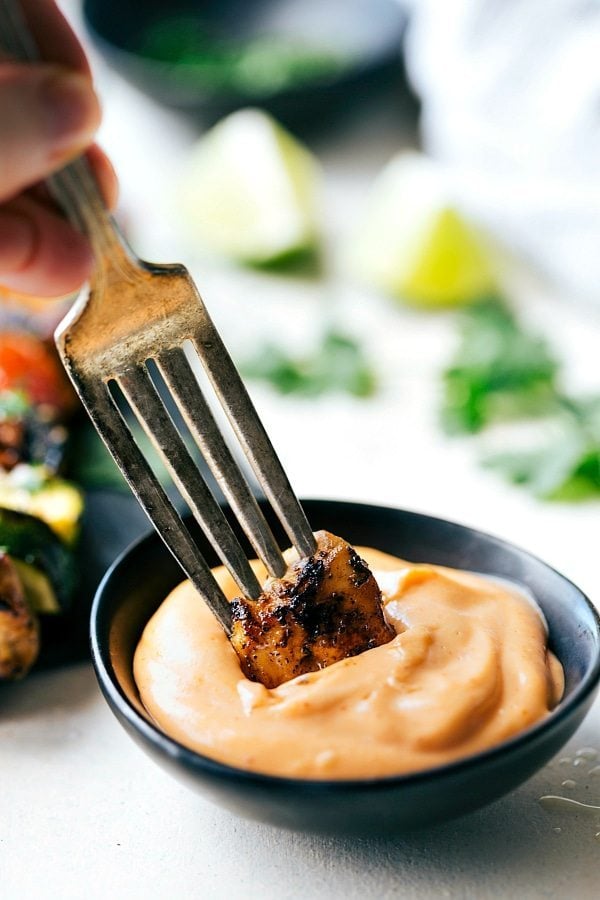 Image of a piece of chicken being dipped in the sauce.