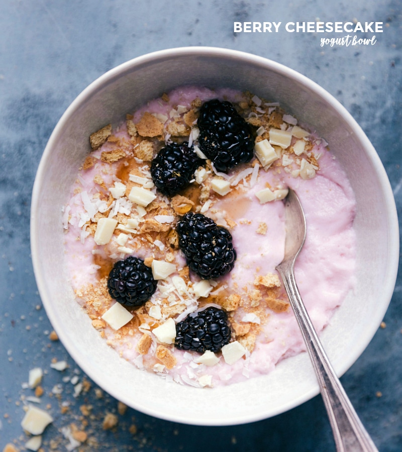 Overhead image of this berry cheesecake Yogurt Bowl with fresh blackberries, crumbled graham crackers, and chopped white chocolate.