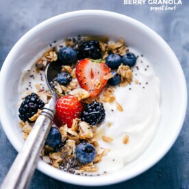 Berry-granola yogurt bowl topped with fresh berries and granola, accompanied by a spoon, prepared for a delightful meal.