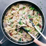 Chicken broccoli alfredo with tongs scooping up a creamy and delicious bite, ready to be enjoyed.