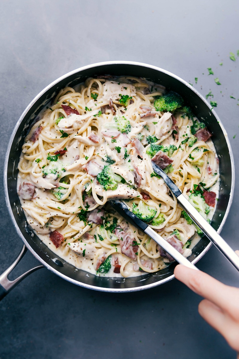 Overhead image of the chicken broccoli Alfredo with tongs scooping some up