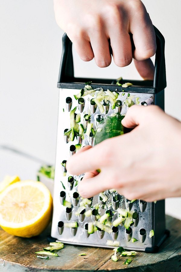 Shredding zucchini on a box grater for the lemon zucchini bread recipe.