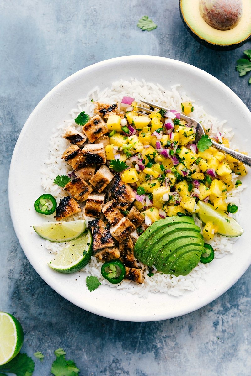 Image of the ready-to-eat Pineapple Chicken over rice, with avocado and lime on the side.