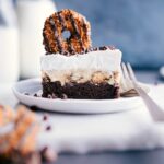 A slice of brownie ice cream bar with a samoas cookie on top, ready to be enjoyed.