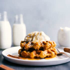 A plate with the finished breakfast, generously topped with whipped cream and drizzled with syrup.