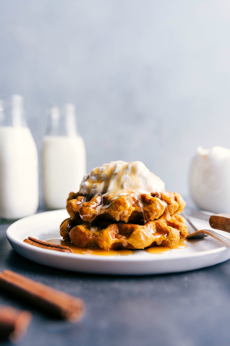 View of two Pumpkin Waffles topped with whipped cream and syrup.