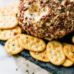 A gorgeous cheese ball with crackers on the side, and a bite scooped out of it, ready to be enjoyed as both a delicious and visually appealing snack.