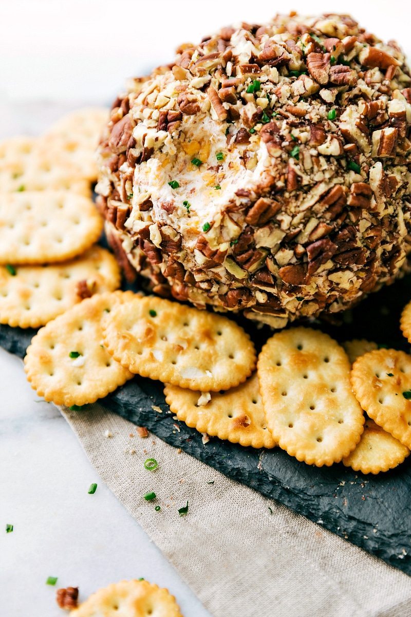 Image of Cheese Ball with crackers on the side, and a bite scooped out of it.