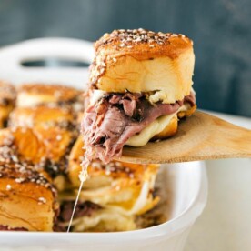 French Dip sandwiches fresh out of the oven with a spatula pulling one out.