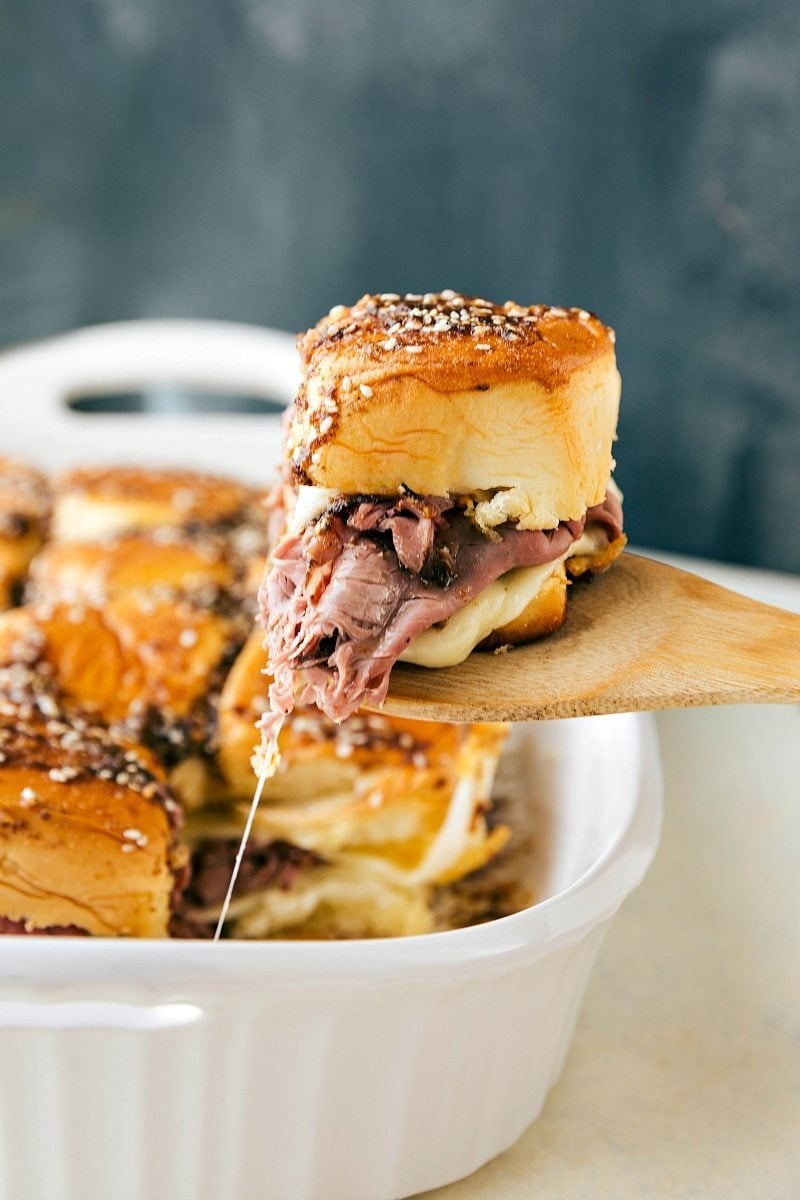 French Dip sandwiches fresh out of the oven with a spatula pulling one out.