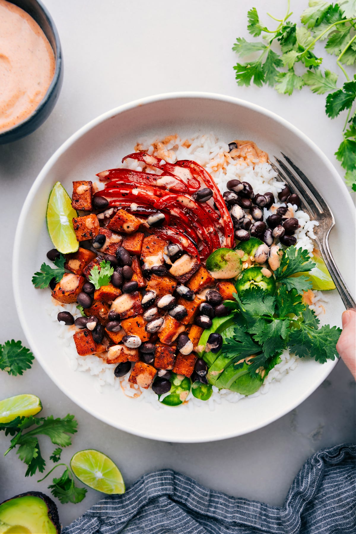 Delicious Sweet Potato and Black Bean Burrito Bowls Sweet Potato and Black Bean Burrito Bowls with dressing drizzled over it.
