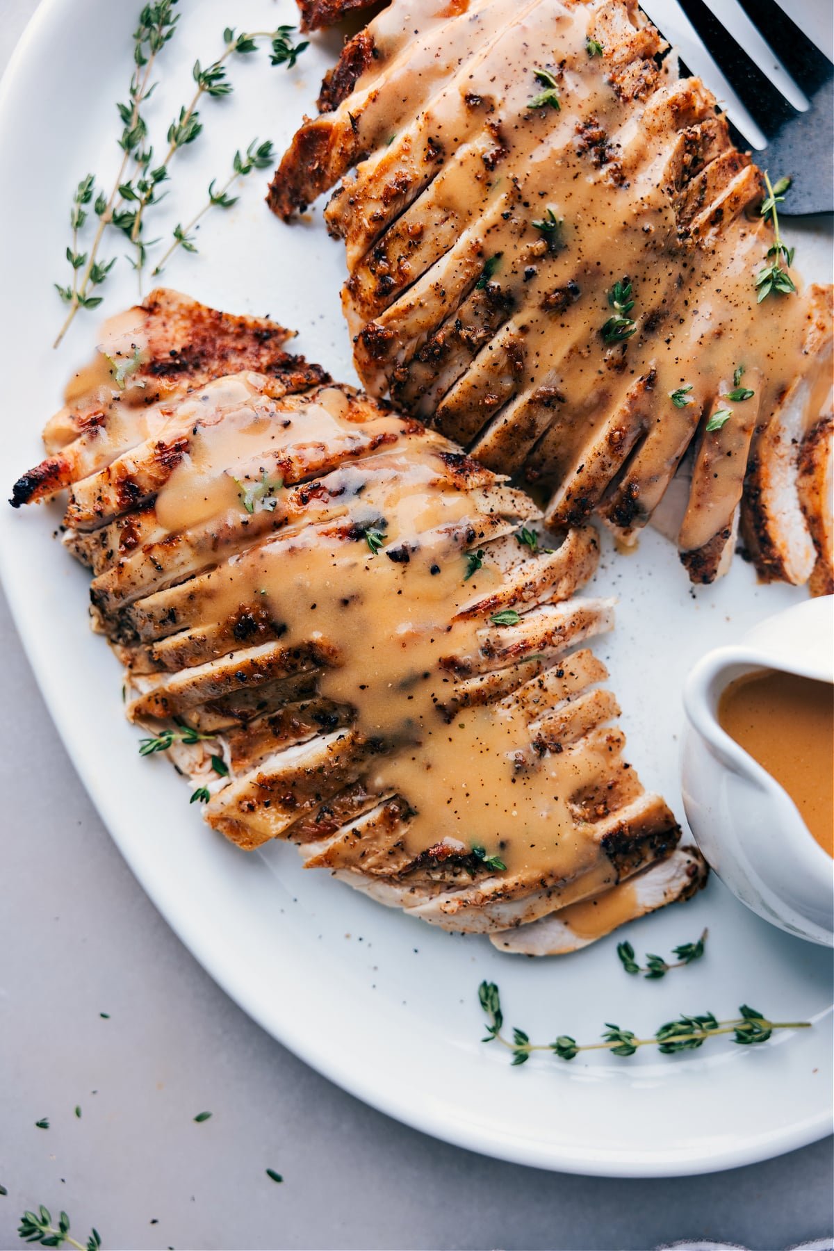 Finished turkey covered in savory gravy, served on a plate, ready for enjoyment.