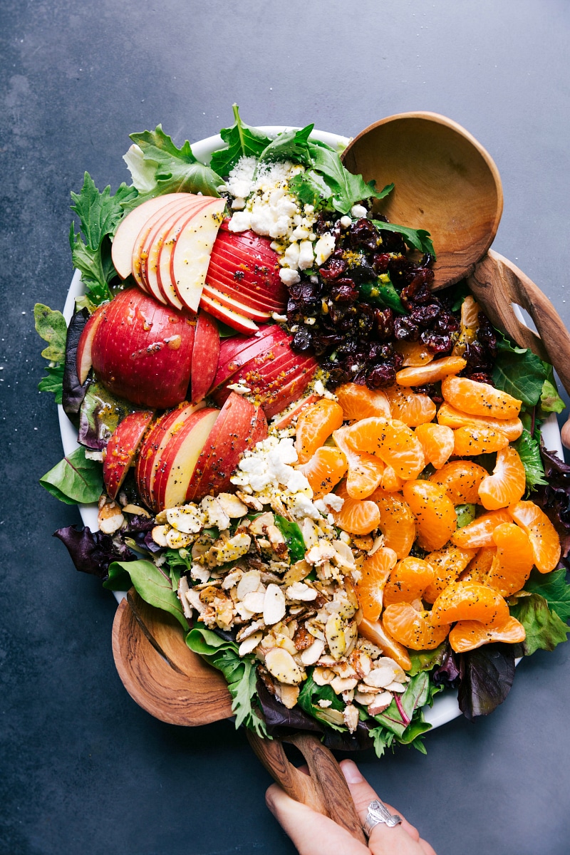 Mandarin orange salad on a large platter, adorned with sliced fruit, presenting a healthy and vibrant dish.