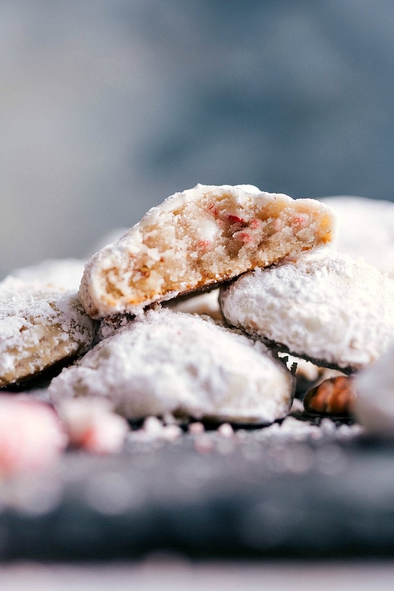 Up-close image of Peppermint Snowball Cookies stacked on top of each other with a bite out of one of them.