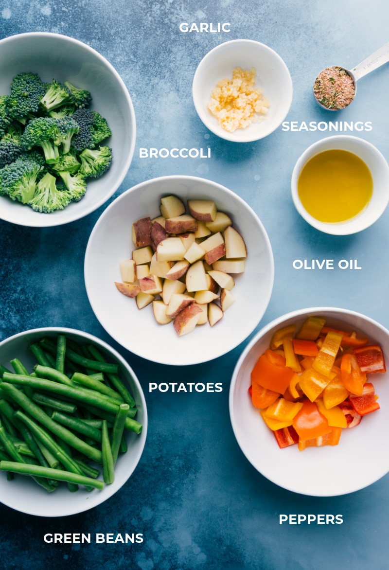 All the roasted veggie ingredients are prepped and ready for easy assembly—broccoli, potatoes, peppers, green beans, seasonings, garlic, and oil.