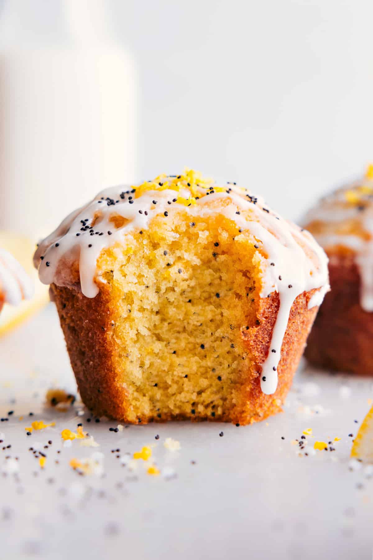 Lemon poppy seed muffin with a fresh bite mark, revealing its moist interior, and adorned with creamy frosting.