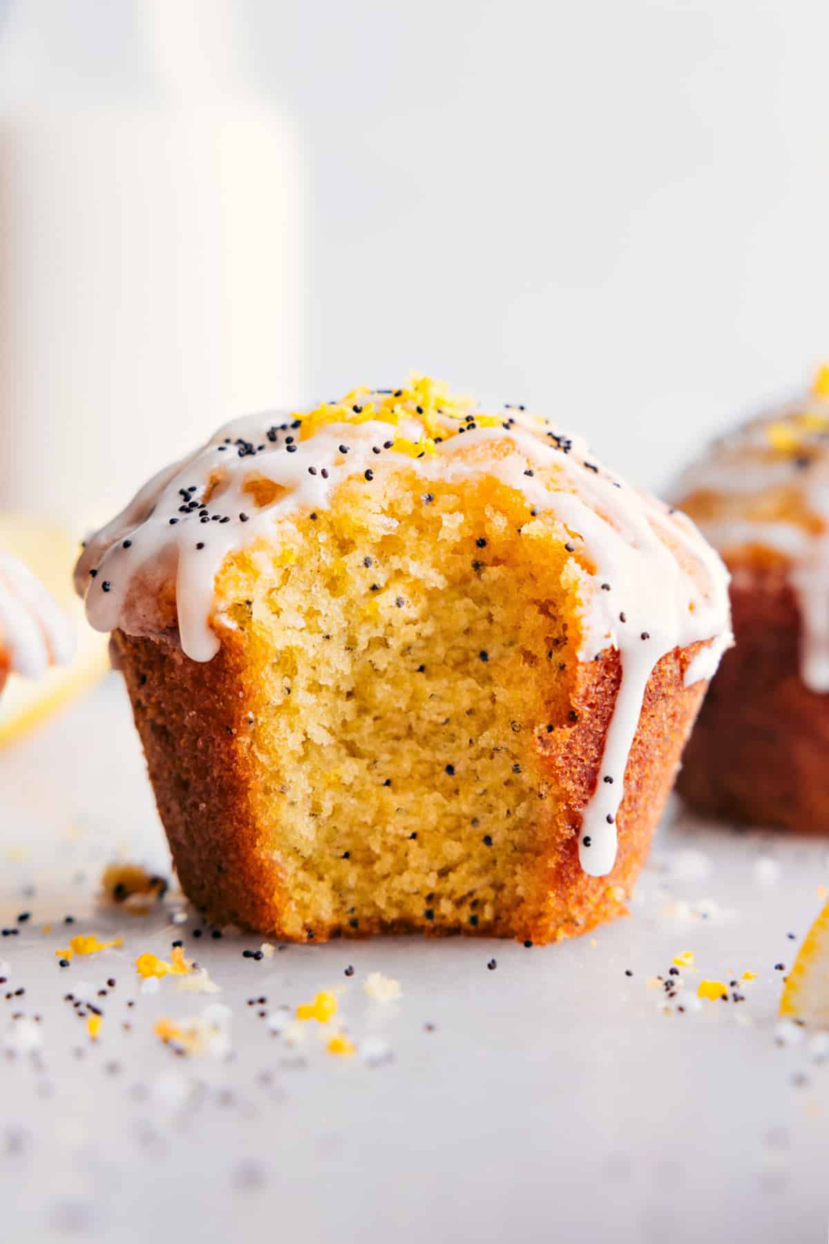 Freshly baked lemon poppy seed muffin with a bite taken out, topped with smooth frosting. Lemon poppy seed muffin with a fresh bite mark, revealing its moist interior, and adorned with creamy frosting.