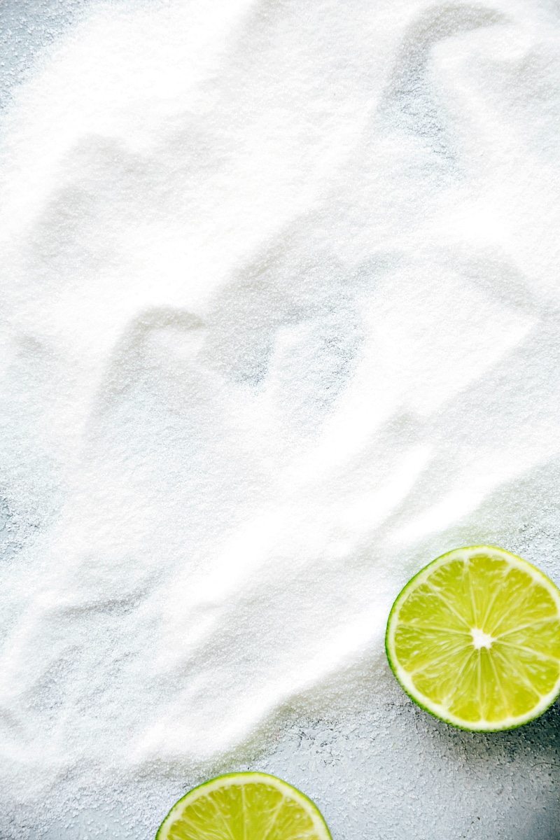 View of halved limes on a bed of white sugar