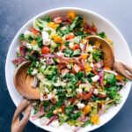 Colorful and vibrant italian chopped salad with wooden serving spoons in the bowl.