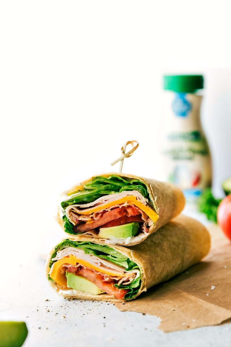 With just a few simple ingredients, you can whip up these tasty and nutritious Turkey Wraps that both kids and adults will love. These wraps are great for busy weeknights when you don't have a lot of time to spend in the kitchen, or for a quick lunch when you're on the go. And best of all, they taste absolutely incredible! Packed with smoky deli turkey, sharp Cheddar cheese, fresh lettuce, juicy tomatoes, and creamy avocado, these wraps are the perfect balance of flavors and textures. Recipe via chelseasmessyapron #lunch #quick #easy #simple #best #familyfriendly #kidfriendly #healthy #nobake #kidfriendly #turkey #wraps Image of the Turkey Wraps stacked on top of eachother