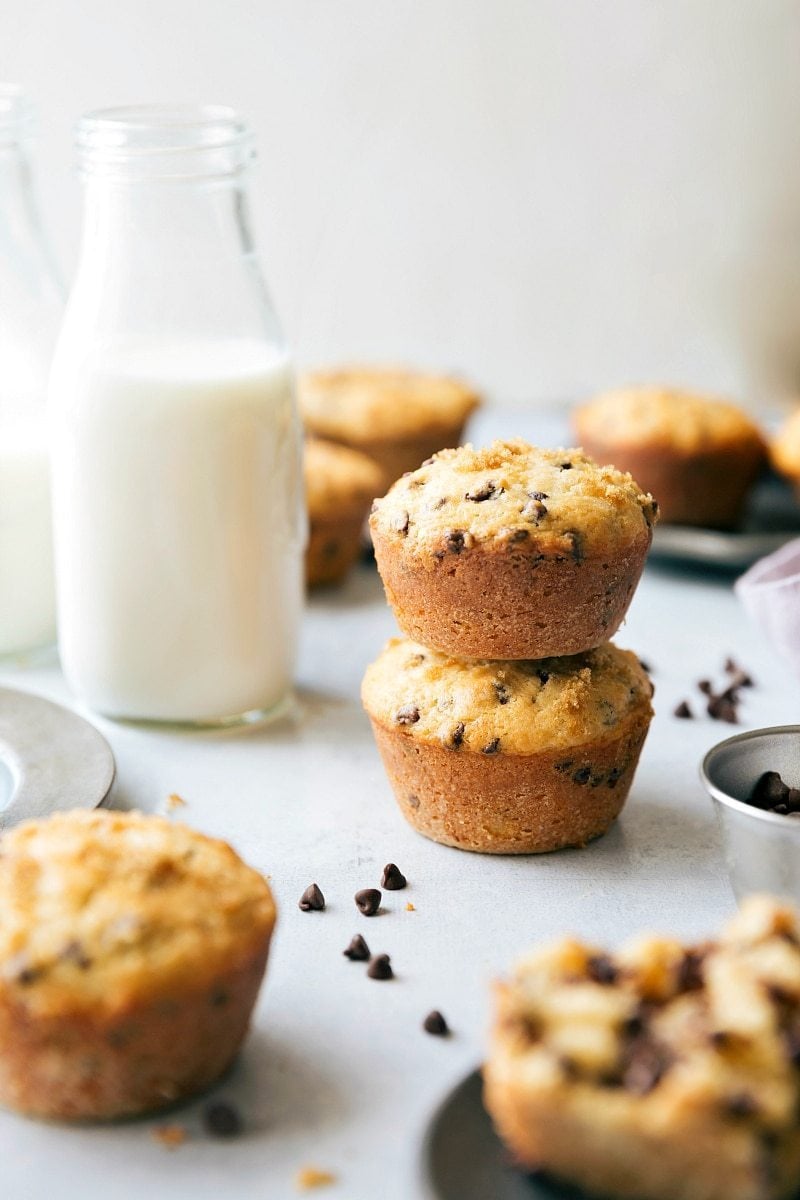 These tender Healthy Chocolate Chip Muffins are made with better-for-you ingredients without sacrificing flavor or texture! They're moist, soft, and every bite is studded with miniature chocolate chips! Recipe via ChelseasMessyApron #dessert #breakfast #quick #easy #simple #treat #snack #milk #healthy #chocolate #chip #muffins Healthy Chocolate Chip Muffins stacked on top of each other