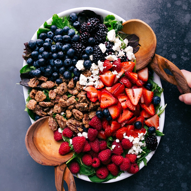 Raspberry salad with healthy and flavorful ingredients on a plate, topped with vinaigrette.