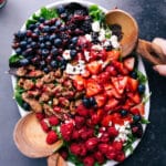 Appetizing salad topped with fresh fruit, cheese, and nuts, ready to be tossed and enjoyed.