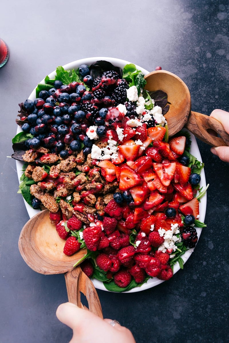 Appetizing salad topped with fresh fruit, cheese, and nuts, ready to be tossed and enjoyed.