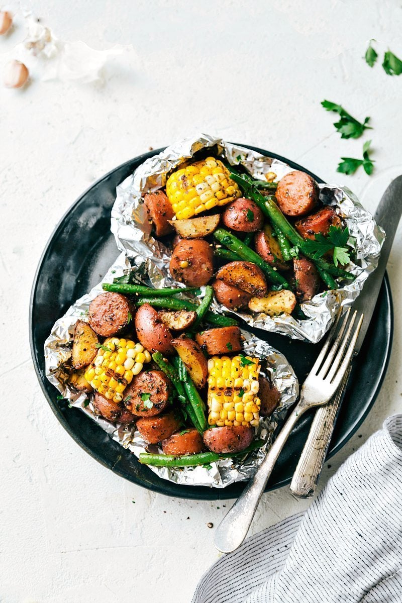 Overhead image of two garlic butter sausage and veggies in foil packs