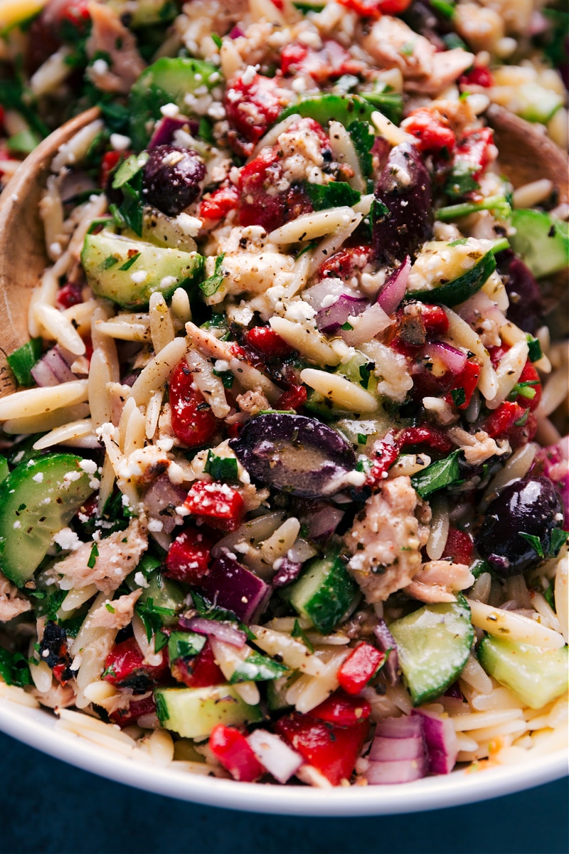 This flavorful Mediterranean Tuna Salad has tender orzo pasta, olive-oil-packed tuna, crisp cucumbers, smoky red peppers, tangy red onions, fresh herbs, and a lemon-oregano vinaigrette. Recipe via ChelseasMessyApron.com #tunasalad #tuna #vinaigrette #mediterranean #orzo #healthy #refreshing Close-up view of the dressed Mediterranean Tuna Salad.