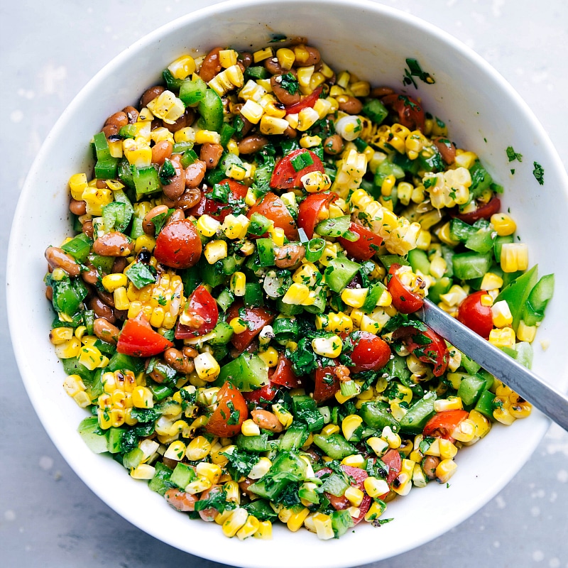 A bowl filled with flavor-packed corn salsa, which serves as a delightful side for this meal, featuring a vibrant blend of ingredients.