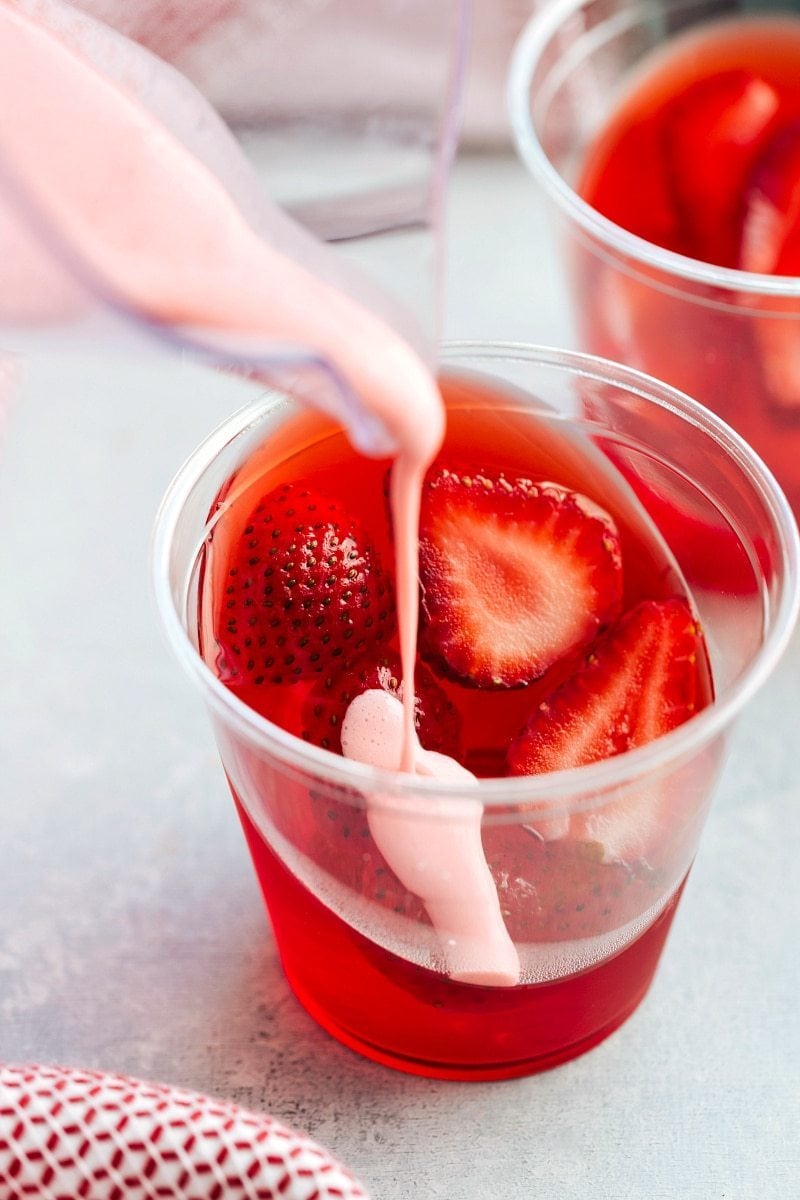 The coolest and EASIEST hack to make these slanted jell-o parfait cups with a strawberry mousse on top. Delicious and so easy!! Recipe from chelseasmessyapron.com