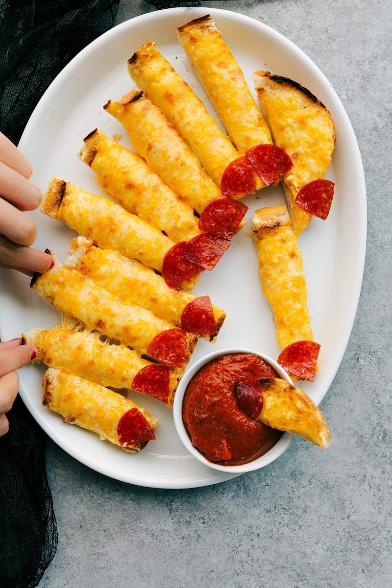 Image of the Cheesy Monster Fingernail Bread, ready to eat and being dipped in marinara, that goes along with these spooky halloween appetizers