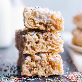 A stack of three delicious rice krispies treats, topped with an assortment of multi-color sprinkles.