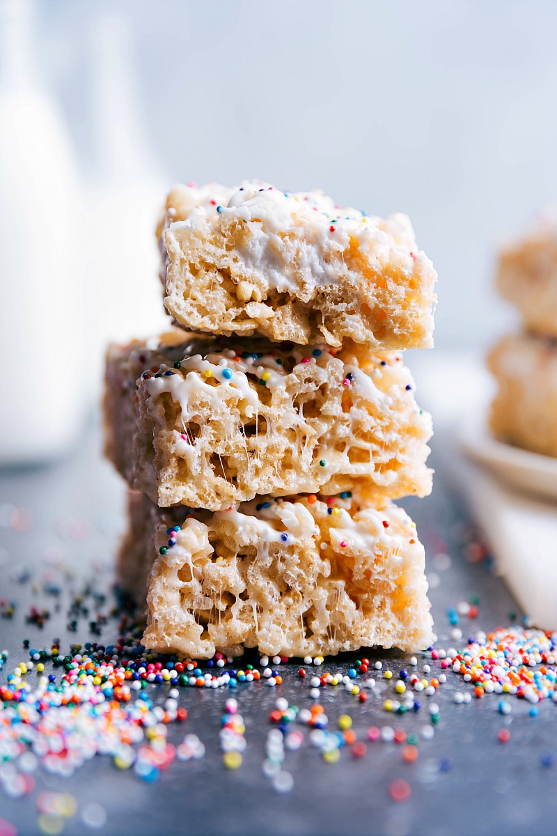 A stack of three delicious rice krispies treats, topped with an assortment of multi-color sprinkles.