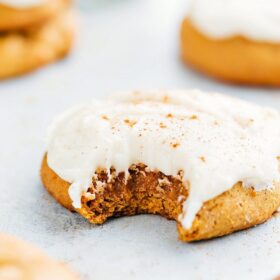 The finished soft pumpkin cookies with cream cheese frosting, one with a bite taken out, showcasing their delightful texture.