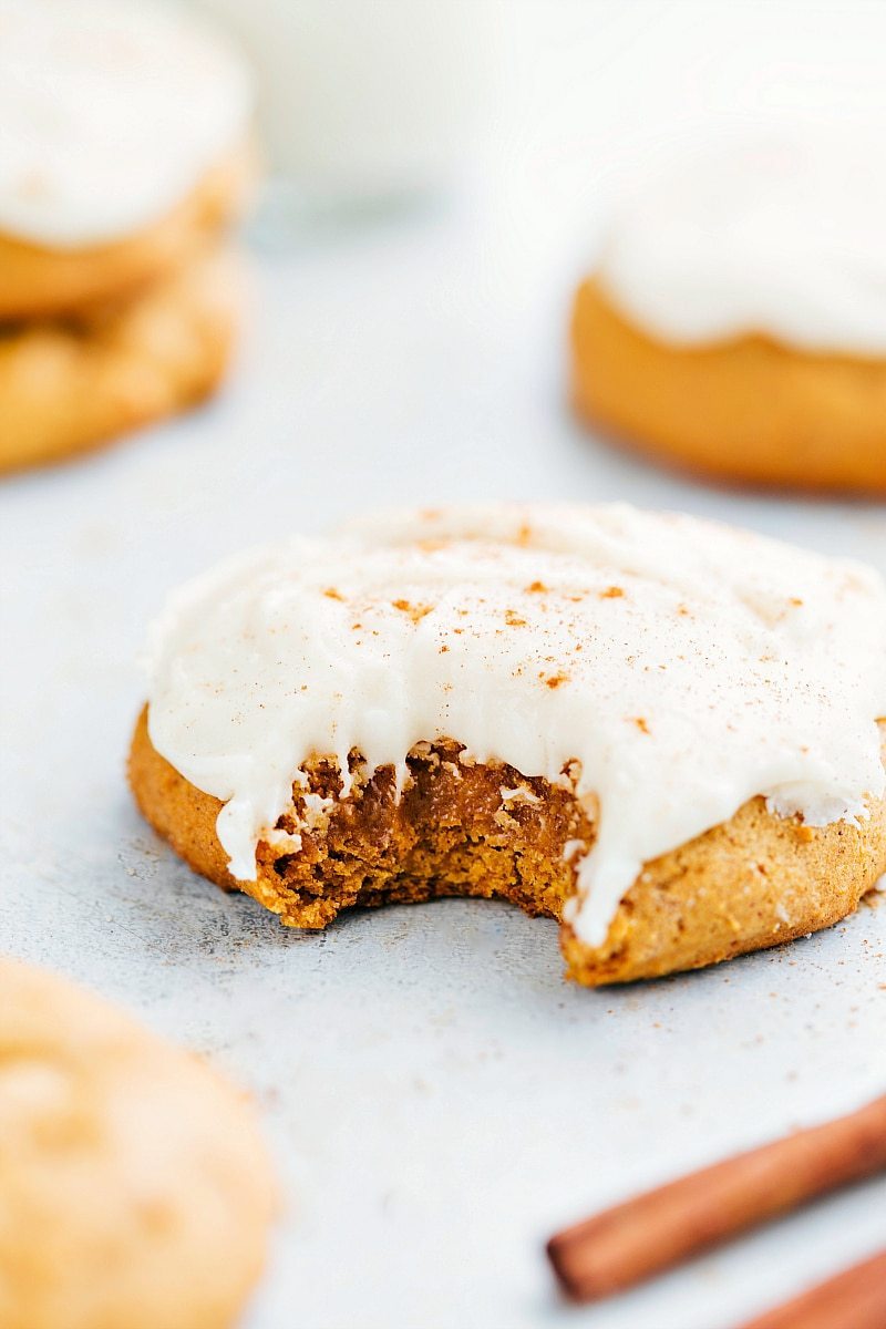 The finished soft pumpkin cookies with cream cheese frosting, one with a bite taken out, showcasing their delightful texture.