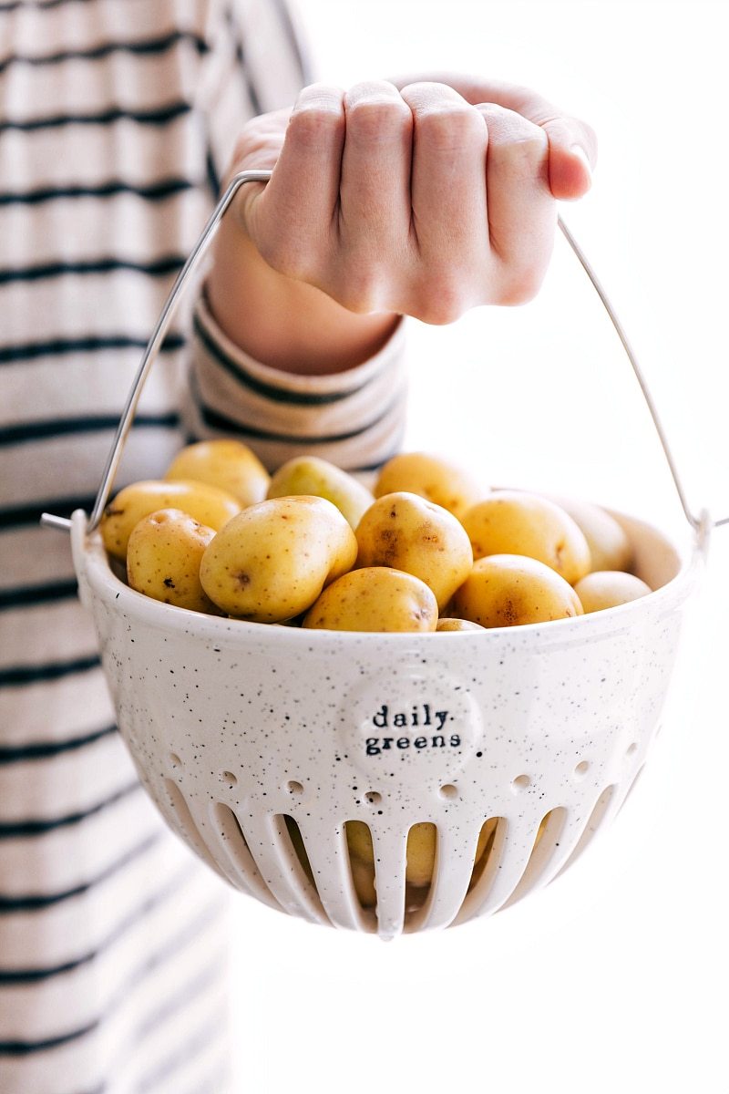 Hand holding strainer with potatoes in it