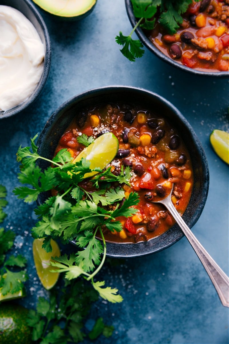 This ridiculously flavorful Taco Chili is better than any restaurant version and is so simple to make -- just empty a bunch of cans in a pot and simmer until you're ready to eat! Load each bowl with your favorite toppings like Cheddar cheese, sour cream, tortilla strips (or chips), fresh lime, and/or cilantro! This chili can be made on the stovetop, pressure cooker, or slow cooker. Recipe via ChelseasMessyApron #dinner #quick #easy #simple #best #corn #beans #healthy #clean #cleaneating #protein #familyfriendly #taco #chili Overhead image of Taco Chili