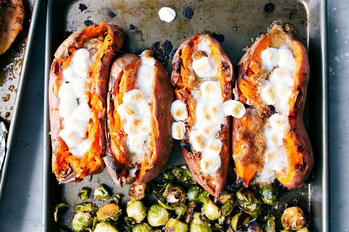 Candied sweet potatoes on a sheet pan with perfectly browned marshmallows, ready to serve.