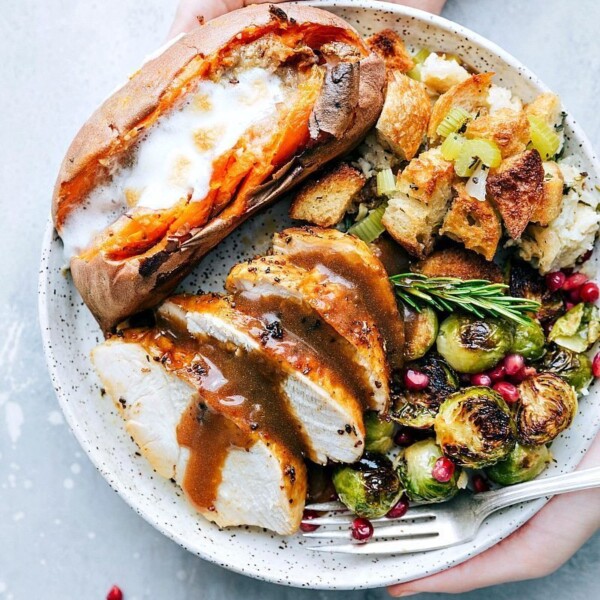 Plate abundantly filled with Thanksgiving staples, including turkey, cranberry sauce, stuffing, and vegetables.