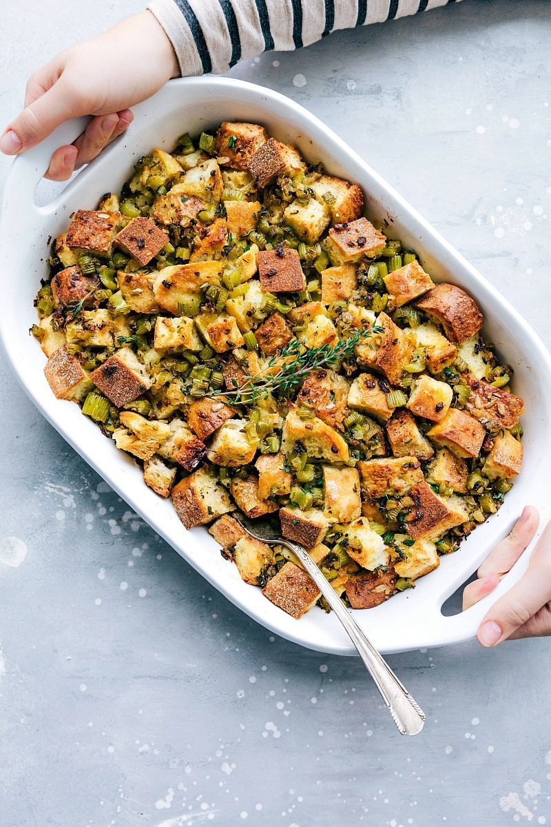 Overhead photo of hands holding a casserole dish filled with Thanksgiving Dressing.