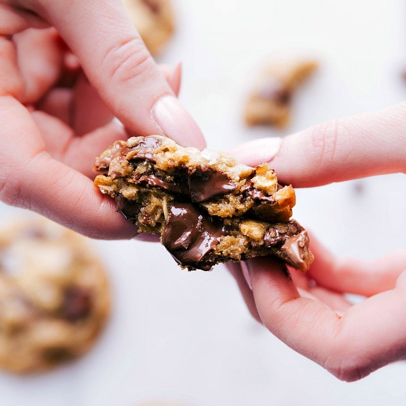 Image of one of the Brown Butter Chocolate Chip Cookies fresh out of the oven, cut in half, showing the gooey inside.