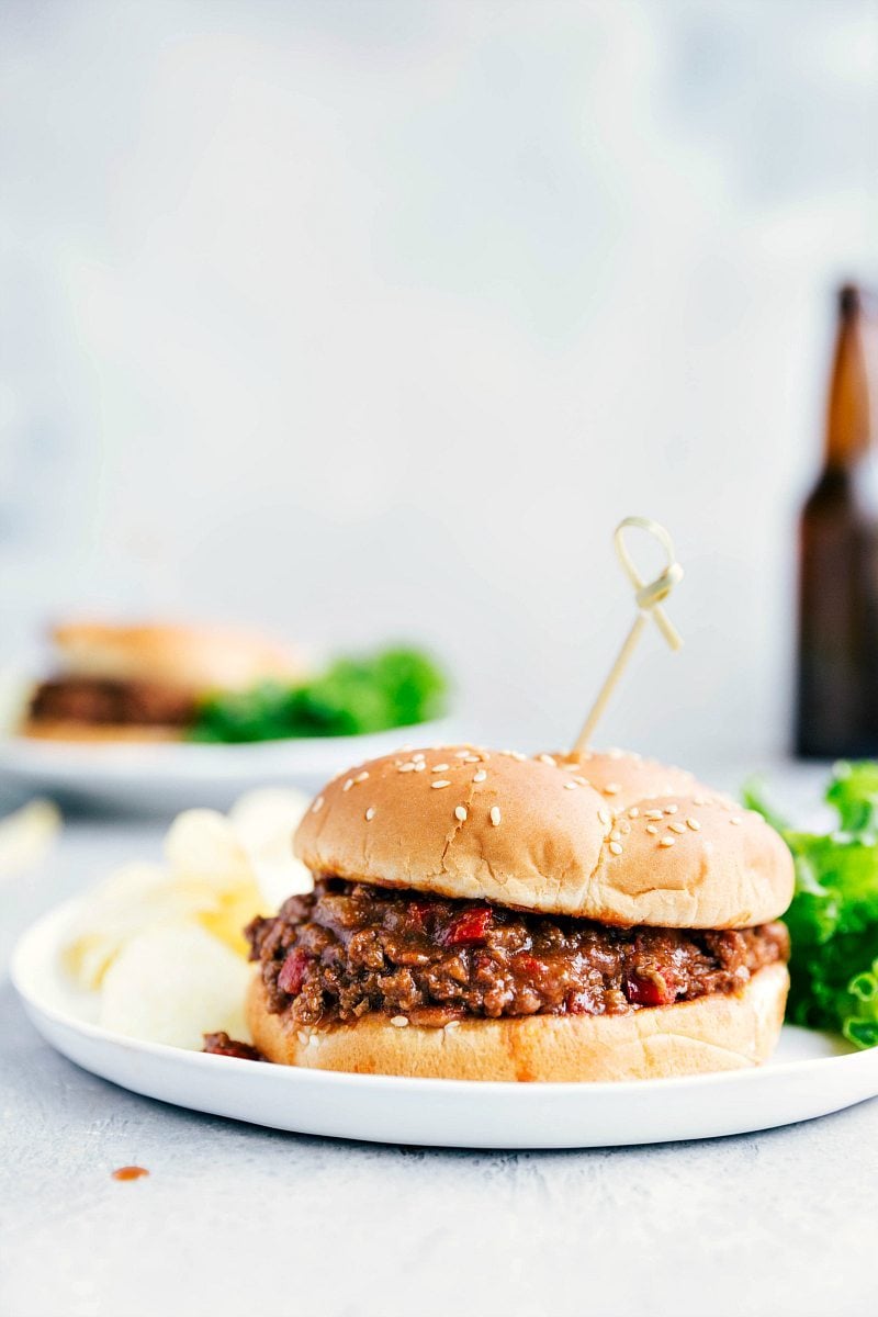 Our favorite Crockpot Sloppy Joes! The slow cooker makes the meat filling ultra-tender and deeply flavorful. We load that savory and slightly sweet meat filling onto toasted brioche buns for a dinner people won't be able to stop raving about! These sandwiches are great to serve to a crowd and perfect for summer BBQs or game-day eating. Recipe via ChelseasMessyApron #dinner #quick #easy #simple #best #chips #bbq #lunch #summer #slowcooker #crockpot #sloppy #joes Crockpot Sloppy Joes on a plate