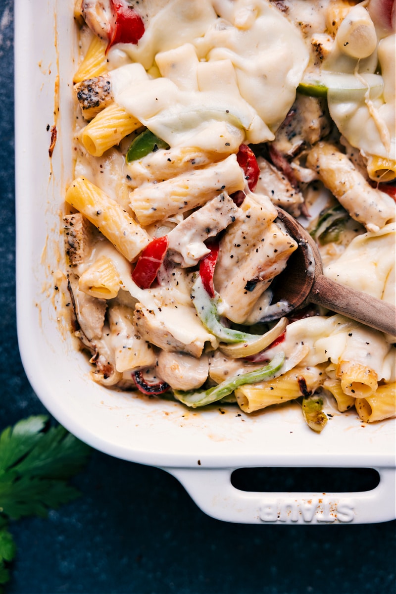 Delicious Baked Ziti With Chicken is a deeply savory and totally indulgent meal the whole family will go crazy for! We're channeling the flavors of a good chicken cheesesteak into this gooey pasta dish by combining perfectly cooked pasta with sautéed peppers and onions, seasoned chicken, and plenty of melty Provolone cheese. Recipe via ChelseasMessyApron.com #chicken #cheesesteak #bakedziti #provolone #casserole #cheesy Closeup view of Baked Ziti with Chicken
