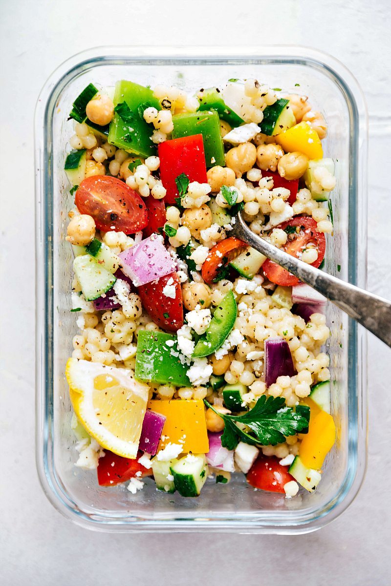 Greek couscous salad dressing and tossed together with a fork in it ready to be enjoyed.