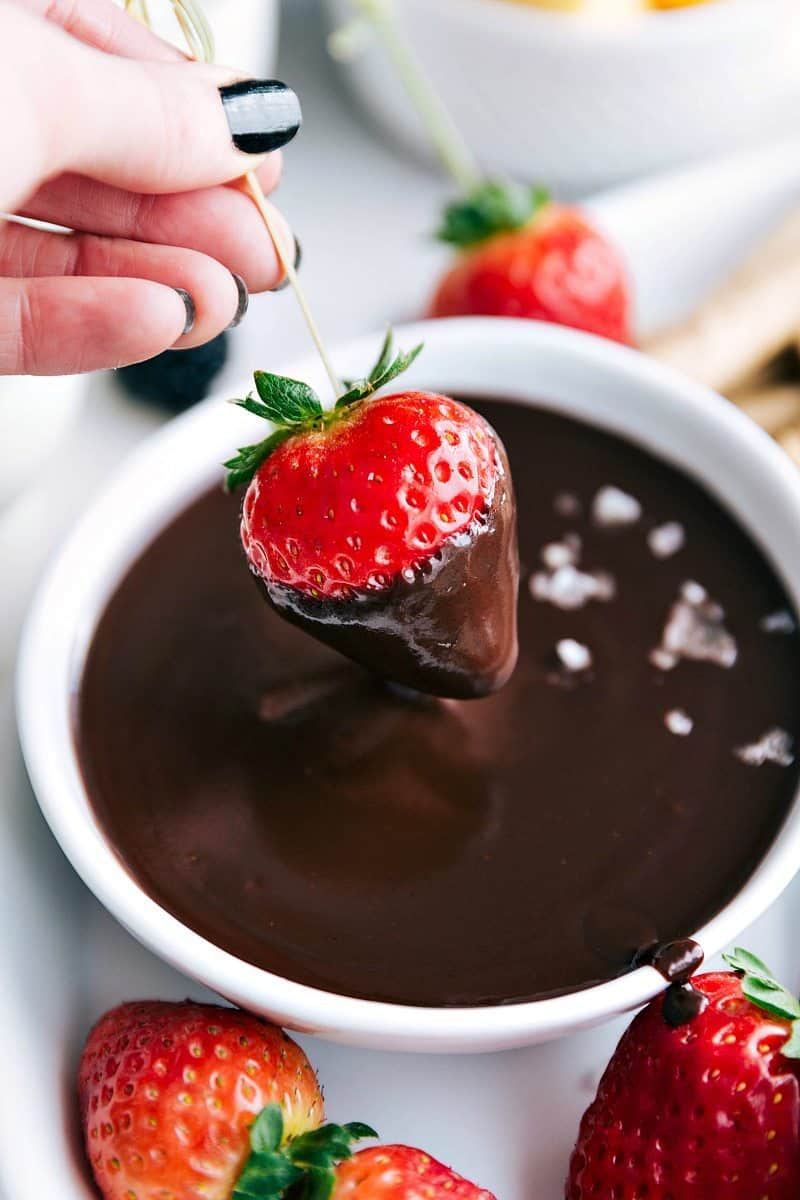 Author dipping strawberry into a bowl of chocolate fondue