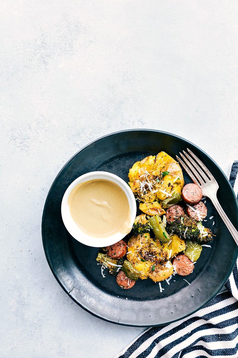 Plate with smashed potatoes, sausage, and veggies with a side of dijonnaise