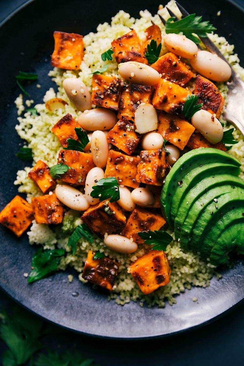 Couscous and sweet potato recipe garnished with fresh herbs and seasonings, served and ready to eat.